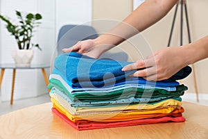 Woman folding bright clothes on table indoors.