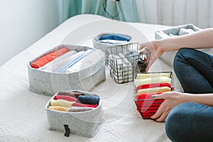 Woman folding clothes, organizing stuff and laundry in boxes