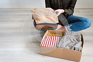 Woman packing clothes into cardboard donation box