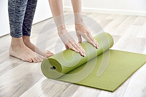 Woman folding yoga or fitness mat after working out at home, Home exercise workout.