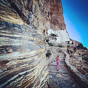 Woman following a stairs to visiting Orthodox monastry of Panagia Hozoviotissa on amorgos island, Greece, Cyclades