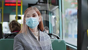 Woman follows modern precautions and wears a medical mask and gloves while traveling on public bus during pandemic and