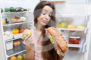 Woman with food near refrigerator