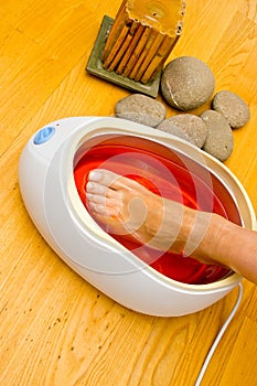 Woman foot in paraffin bath at the spa