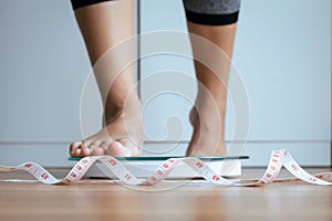 Woman foot stepping on weigh scales with tape measure in foreground,Weight loss,Body and good health concept