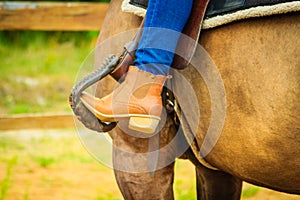 Woman foot in stirrup on horse saddle