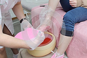 woman foot treatment in paraffin bath at the spa.