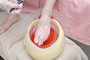 woman foot treatment in paraffin bath at the spa.