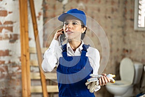 Woman foreman talking on a mobile phone inside building under construction