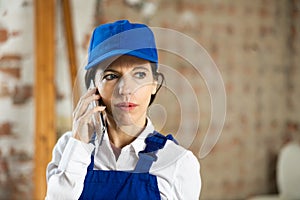 Woman foreman talking on a mobile phone inside building under construction