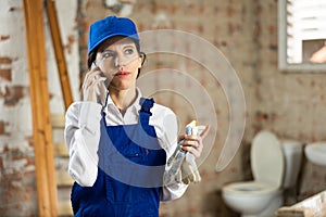 Woman foreman talking on a mobile phone inside building under construction