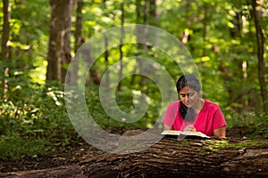Woman in Forest Preserve with Bible Kneeling in Prayer