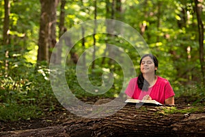 Woman in Forest Preserve with Bible Kneeling in Prayer photo