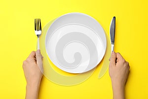 Woman with fork, knife and empty plate, top view