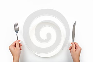 Woman with fork, knife and empty plate on on a on a white background, top view