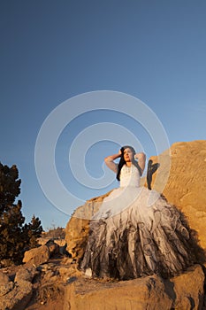 Woman formal rocks hands up blue sky