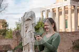 Woman in foro romano texting with the smartphone