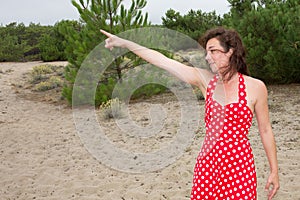 Woman forties wearing red and white sixties dress pointing away finger