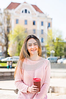 Woman at Fountain with Phone and coffee to takeaway on city street