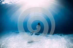 Woman freediver in bikini over sandy sea with fins. Freediving underwater