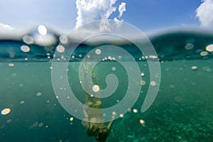 Woman freediver glides with fins over ocean with air bubbles