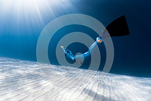 Woman freediver glides over sandy bottom