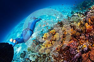 Woman freediver glides over vivid coral reef