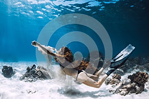 Woman freediver swim underwater over sandy bottom with sand