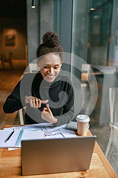 Woman freelance architect talking with client via video call and discuss project sitting in cafe