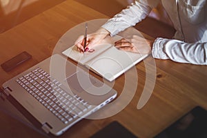 Woman freelancer female hands with pen writing on notebook at home or office.