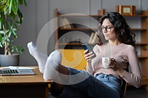 Woman freelancer procrastinate from work. Female distracted from laptop scroll social media on phone
