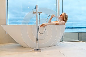 woman in freestanding white bath. Modern bathroom interior design. Beauty, healthy lifestyle concept