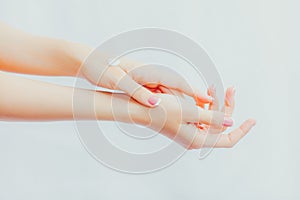 Woman with french manicure applies cream to her hands