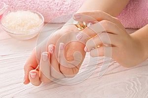 Woman with French manicure applies perfume on wrist