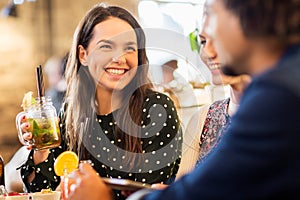 Woman with friends drinking cocktail at restaurant