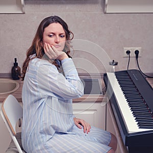 Woman with fright in her eyes looks at home digital piano, problems with playing musical instruments