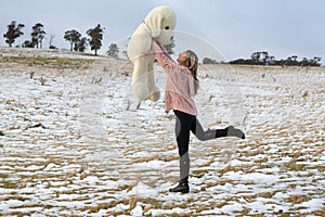 Woman frolicking in the snow with teddy bear