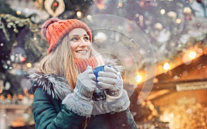 Woman in front of Christmas tree on winter market drinking hot wine