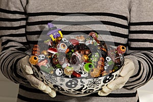 Woman at the front door offering Halloween candies on a nice bowl. Protect for COVID-19