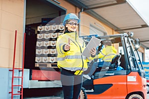 woman in front of forklift transporting goods from warehouse