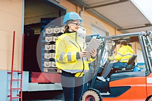 woman in front of forklift transporting goods from warehouse