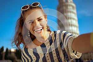 Woman in front of leaning tower in Pisa, Italy taking selfie