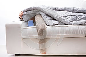 Woman, front lying, white couch, warm quilt, flu, weak arm, hot