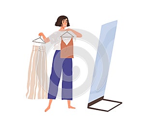 Woman in front of mirror deciding what to wear. Female choosing clothes, holding apparel on hangers, preparing to go out