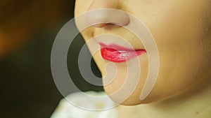 A woman in front of a mirror paints her lips with red lipstick