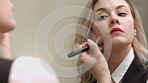 Woman in front of mirror putting make up on