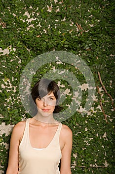 Woman in front of wall of leaves