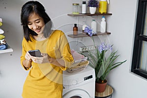 woman in front of the washing machine using phone