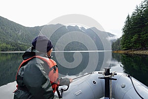 A woman at the front of a zodiac on a tour exploring the ocean, coastlines, forest and islands of Gwaii Haanas, Haida Gwaii