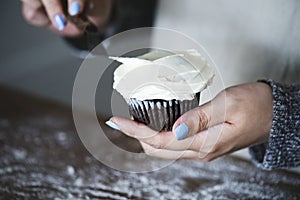 Woman frosting a cupcake baking